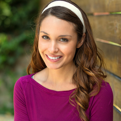 A young woman with long hair and a headband, smiling at the camera.