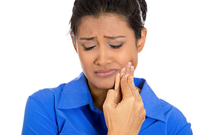 A woman with her eyes closed, holding a toothbrush to her mouth.