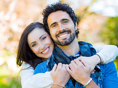 Man and woman smiling together, man in blue shirt, woman in white top.