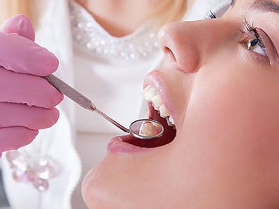 A dental professional is performing a procedure on a patient s teeth, using specialized tools.