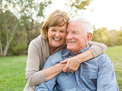 The image depicts a man and woman in an outdoor setting, embracing each other.