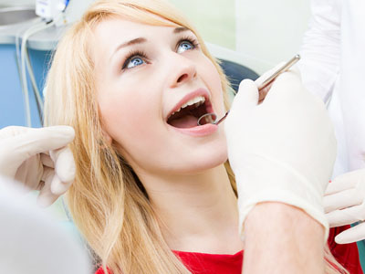 A woman receiving dental care, smiling broadly while looking upwards.