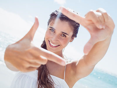 A woman is taking a selfie with her hands held up to frame the photo.